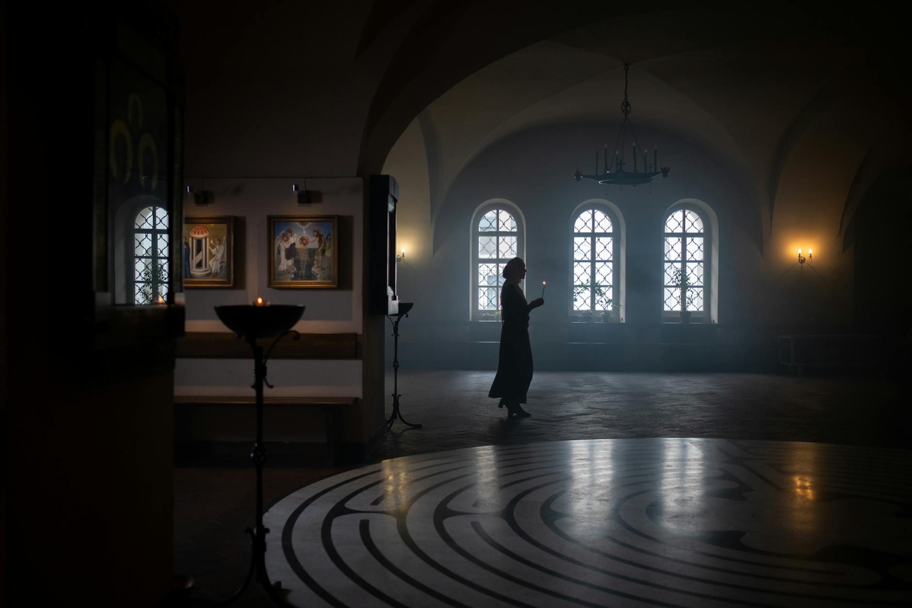 Osoba idąca z zapaloną świecą w ciemnym korytarzu świątyni