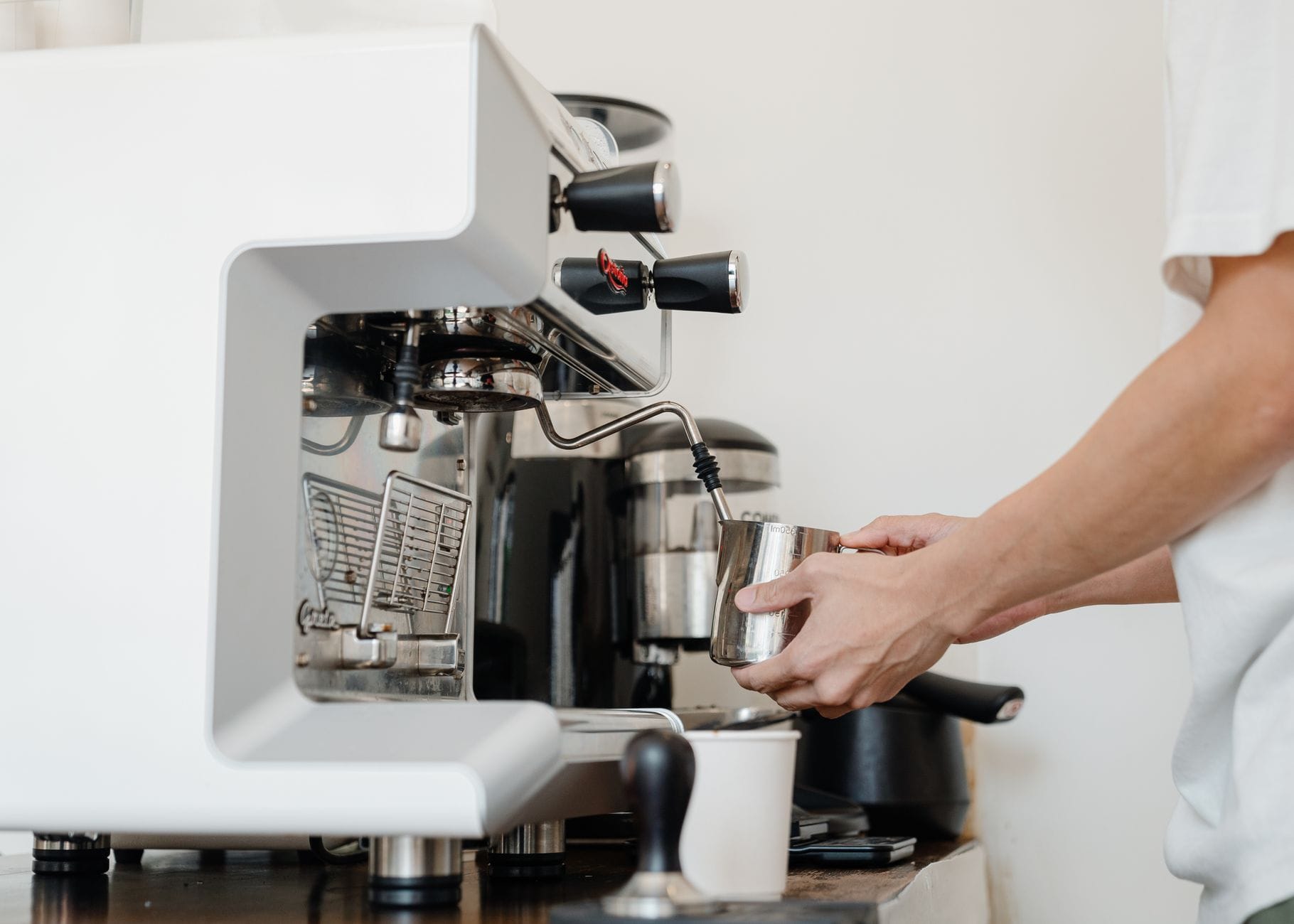 Dłonie baristy przygotowujące espresso w ekspresie ciśnieniowym