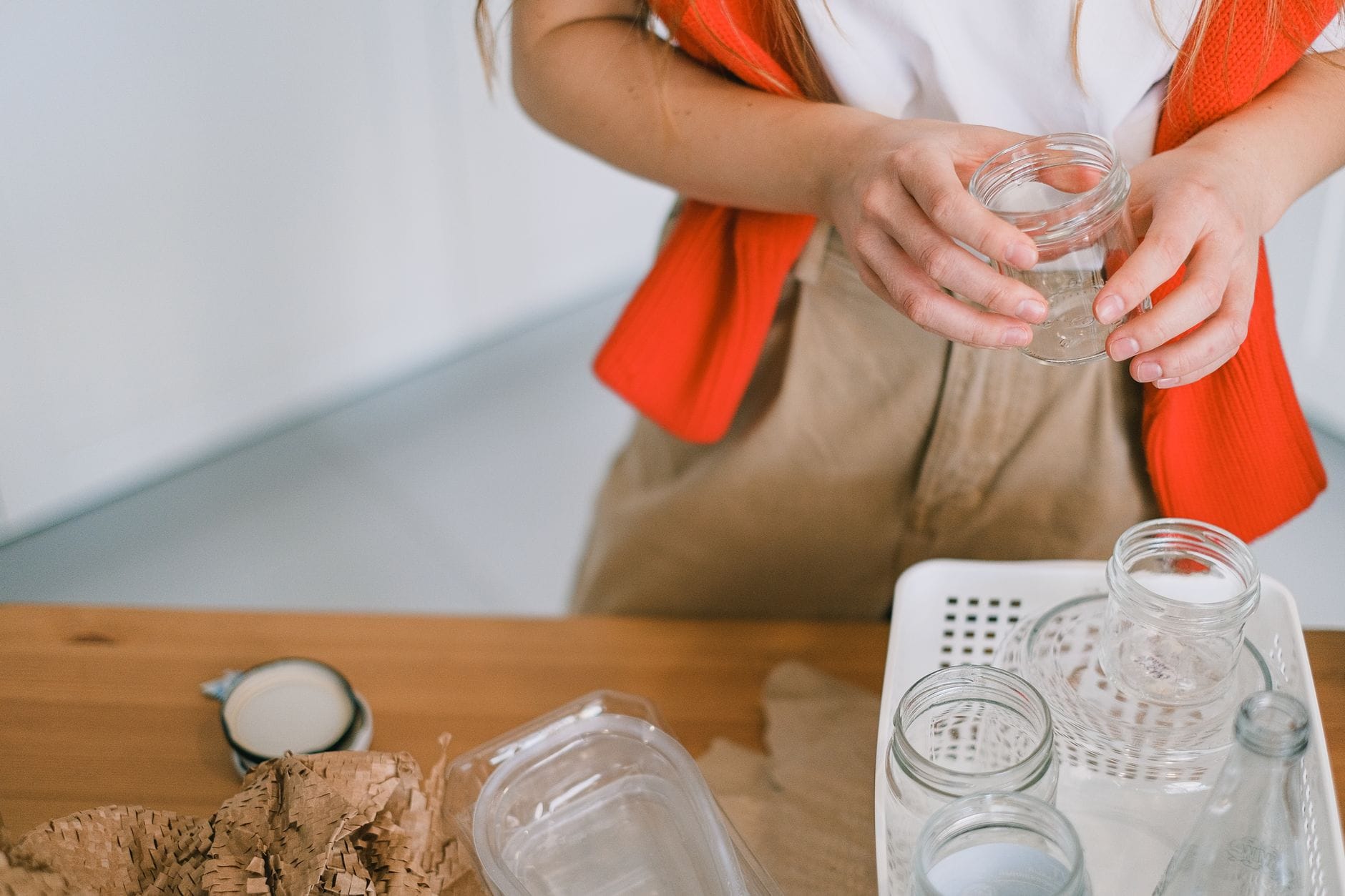 Kobieta segreguje szkło i papier do recyklingu przy kuchennym blacie Kobieta segreguje szkło i papier do recyklingu przy kuchennym blacie